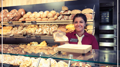 Bäckereiverkäuferin reicht Brottüte über die Theke